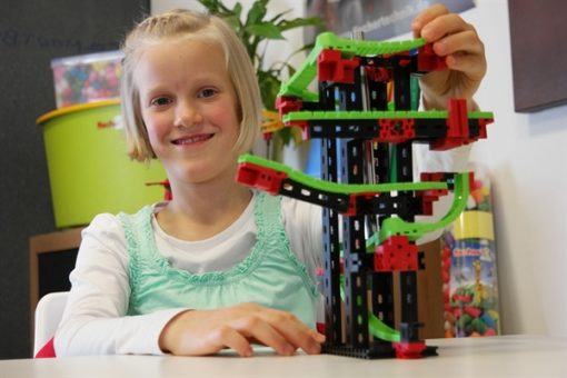 Dziewczynka chwali się złożoną przez siebie konstrukcją z labiryntm dla kulek